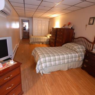 A spacious bedroom with twin beds, wooden flooring, and classic furniture.