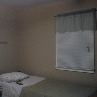 A simple bedroom with a single bed and a window with blinds.