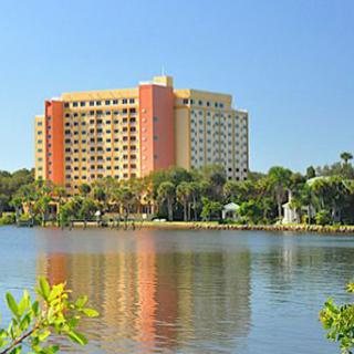 A hotel building with a scenic view of a lake and palm trees.