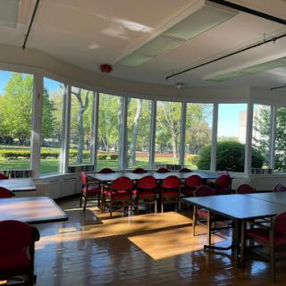 A bright and inviting classroom bathed in natural light, featuring large windows that showcase the lush greenery outside.