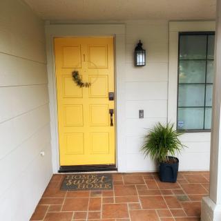 A welcoming front porch with a bright yellow door and potted plant.