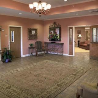 A spacious lobby with elegant decor, featuring a chandelier, carpet, and classic furniture pieces.