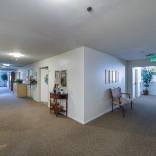 A spacious hallway with doors and seating, brightly lit in an office setting.