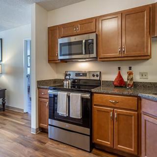 A modern kitchen with wooden cabinets, stainless steel appliances, and a hardwood floor.