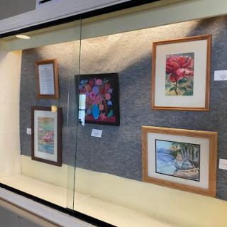 A display of various framed paintings showcased in an art gallery.