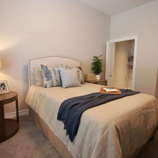 A cozy and well-decorated bedroom with a neatly made bed, soft lighting, and a touch of greenery.