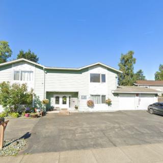 A suburban house with a wide driveway and parked car under a clear blue sky.