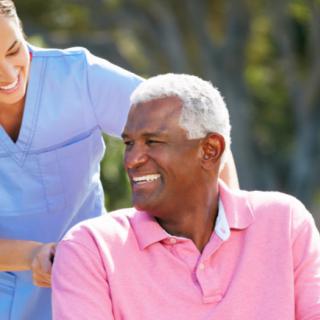 An elderly man receiving care from a smiling caregiver outdoors.