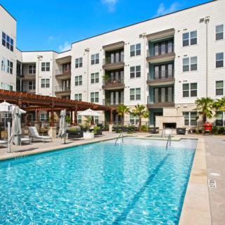 A luxurious apartment complex featuring a spacious outdoor swimming pool and modern design.