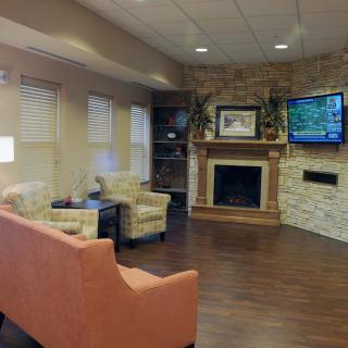 A cozy waiting area featuring comfortable seating, a fireplace, and a television.