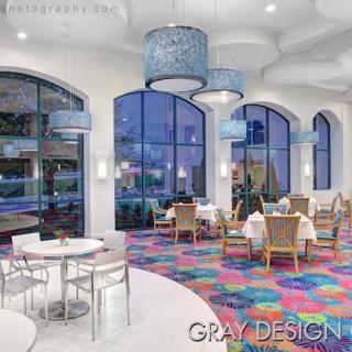 A modern restaurant interior featuring colorful flooring and large arched windows.