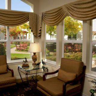 A cozy living room with armchairs and large windows overlooking a garden.