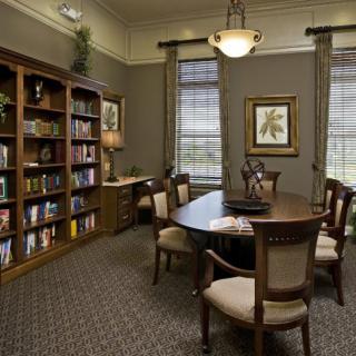 A well-lit library conference room with bookshelves, a central table, and several chairs.