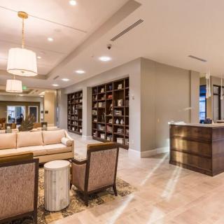 A modern lobby with comfortable seating, stylish lighting fixtures, and a wall-mounted bookshelf.