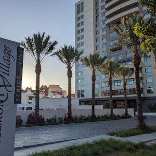 A modern residential building surrounded by palm trees, showcasing a blend of urban architecture and nature.