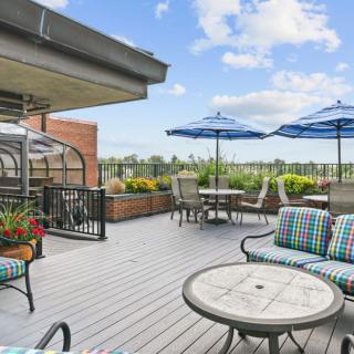 A rooftop patio with outdoor seating, umbrellas, and a view of the cityscape under a clear sky.