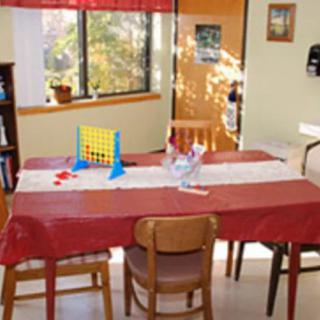 A room with a table set up for a board game, surrounded by chairs and featuring a window view.