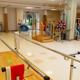 A physical therapy room equipped with various exercise tools and parallel bars for rehabilitation exercises.