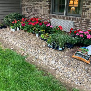 A garden area prepared with flowers and plants for landscaping near a house.