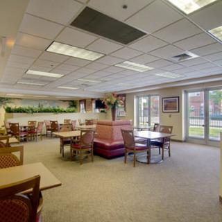 Spacious restaurant interior with tables and chairs, featuring large windows and ceiling lights.