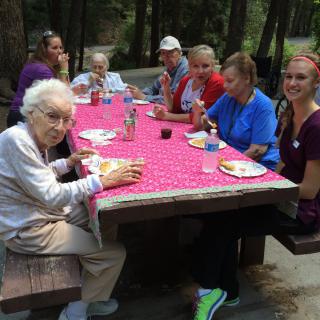 A group of people enjoying a picnic together in a forest setting.