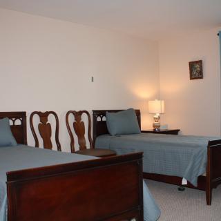 A cozy bedroom featuring two twin beds with blue bedding and warm wooden furniture.