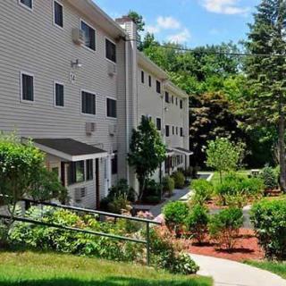 A well-maintained apartment building surrounded by lush greenery and landscaped gardens on a sunny day.