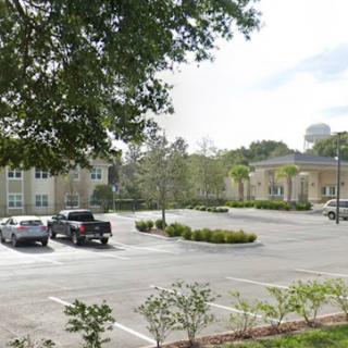 A view of a spacious parking lot with several vehicles and landscaped greenery in a residential neighborhood.
