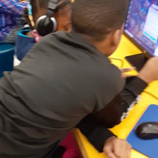 Two children engaged in learning at a computer station.