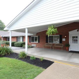 A welcoming exterior view of a residential building with a front porch and well-maintained landscaping.