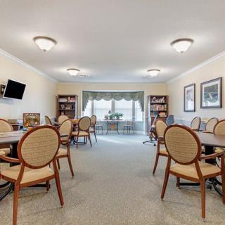 A spacious meeting room with tables, chairs, and bookshelves under soft lighting.