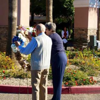 Two individuals placing a floral wreath during a memorial ceremony.