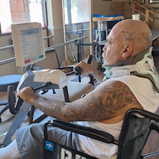 A patient engaged in a rehabilitation exercise using adaptive equipment.