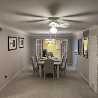 A modern dining room with a table set for six, featuring a ceiling fan and contemporary artwork.