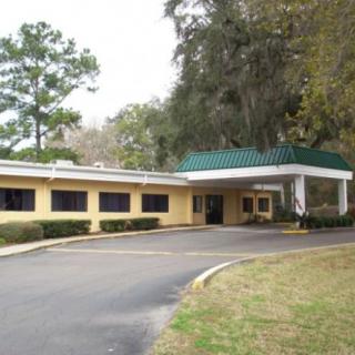 A building entrance with a driveway surrounded by trees and landscaping.