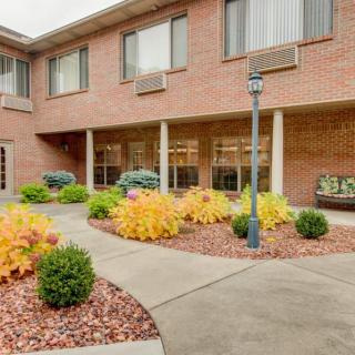A neatly landscaped courtyard in front of a brick building with windows.