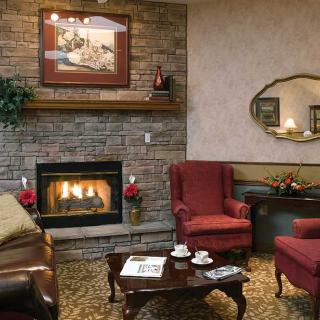 A cozy living room with a fireplace, traditional decor, armchairs, and a coffee table.