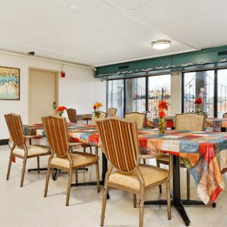 A well-lit dining area featuring neatly set tables with floral decorations, perfect for community gatherings.