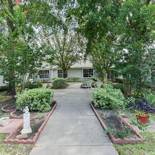 A residential house with a landscaped front yard and walkway surrounded by trees.