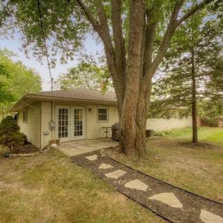 A quaint backyard with a small house, featuring a large tree and stepping stone pathway.
