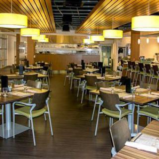 A modern restaurant interior with neatly arranged tables and chairs, featuring stylish lighting.