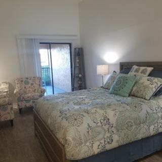 A cozy bedroom with a patterned bedspread, decorative pillows, and matching chairs.