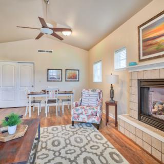 A cozy living room featuring a fireplace, ceiling fan, and stylish decor with a view into the dining area.