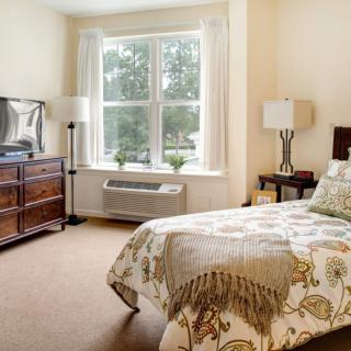 A cozy bedroom with a single bed, large window, and elegant furnishings.