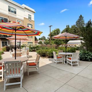 A sunny patio with colorful umbrellas and outdoor seating in a garden setting.