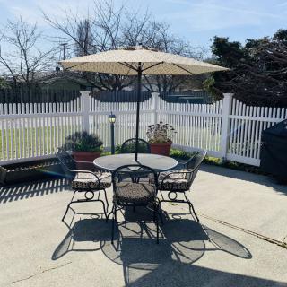 A sunny outdoor patio with a table, chairs, and an umbrella.