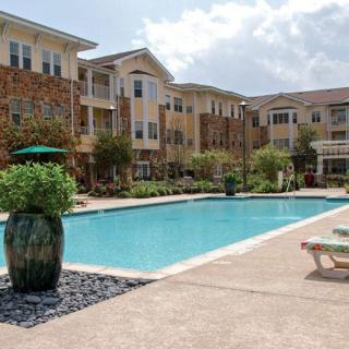 A modern apartment complex with an inviting outdoor swimming pool surrounded by lush landscaping.