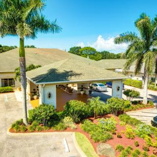 A tropical house surrounded by palm trees on a sunny day.