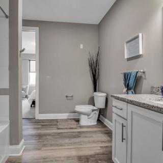 A modern bathroom with neutral tones, featuring a toilet, sink, mirror, and elegant decor.