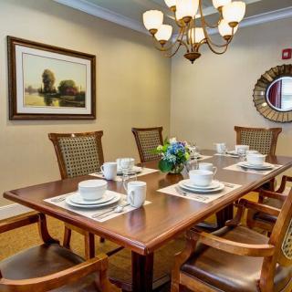A beautifully set dining room table with a chandelier overhead, featuring elegant place settings and a centerpiece of flowers.